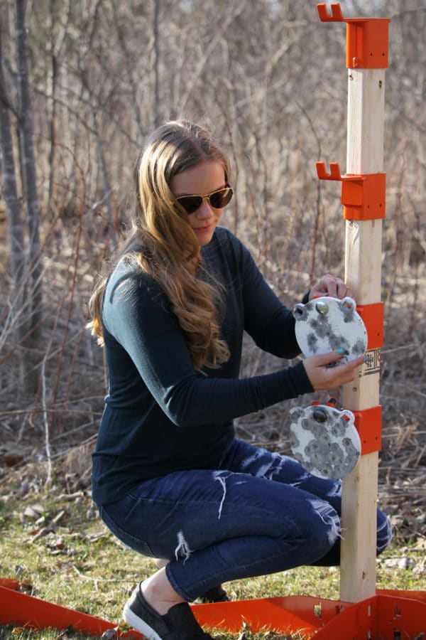 Woman adjusts a 6 inch round gong target on a 2x4 slider